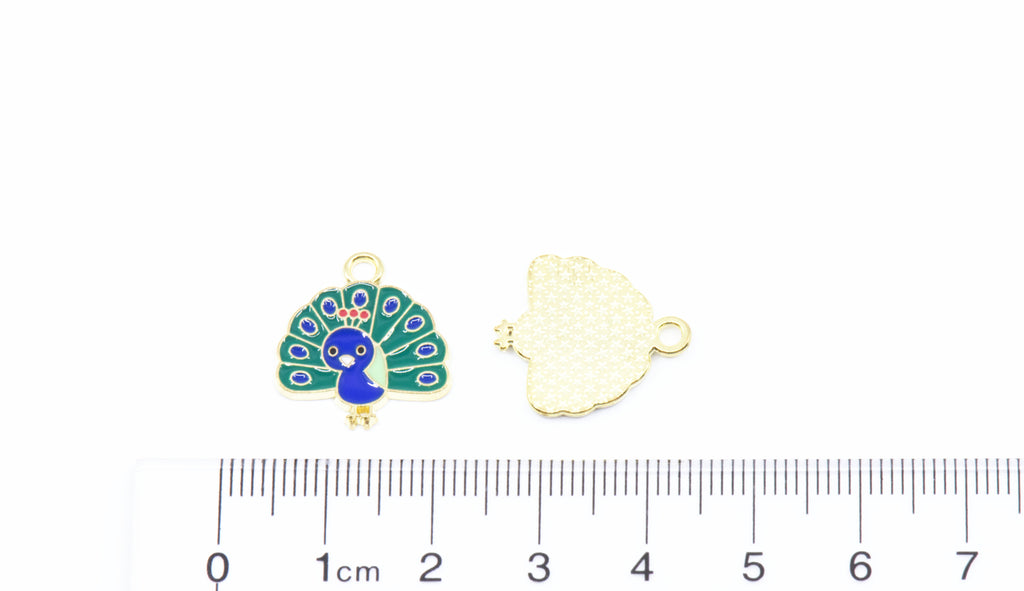 Two peacock jewelry charms shown on a white background with a ruler at the bottom for scale: 