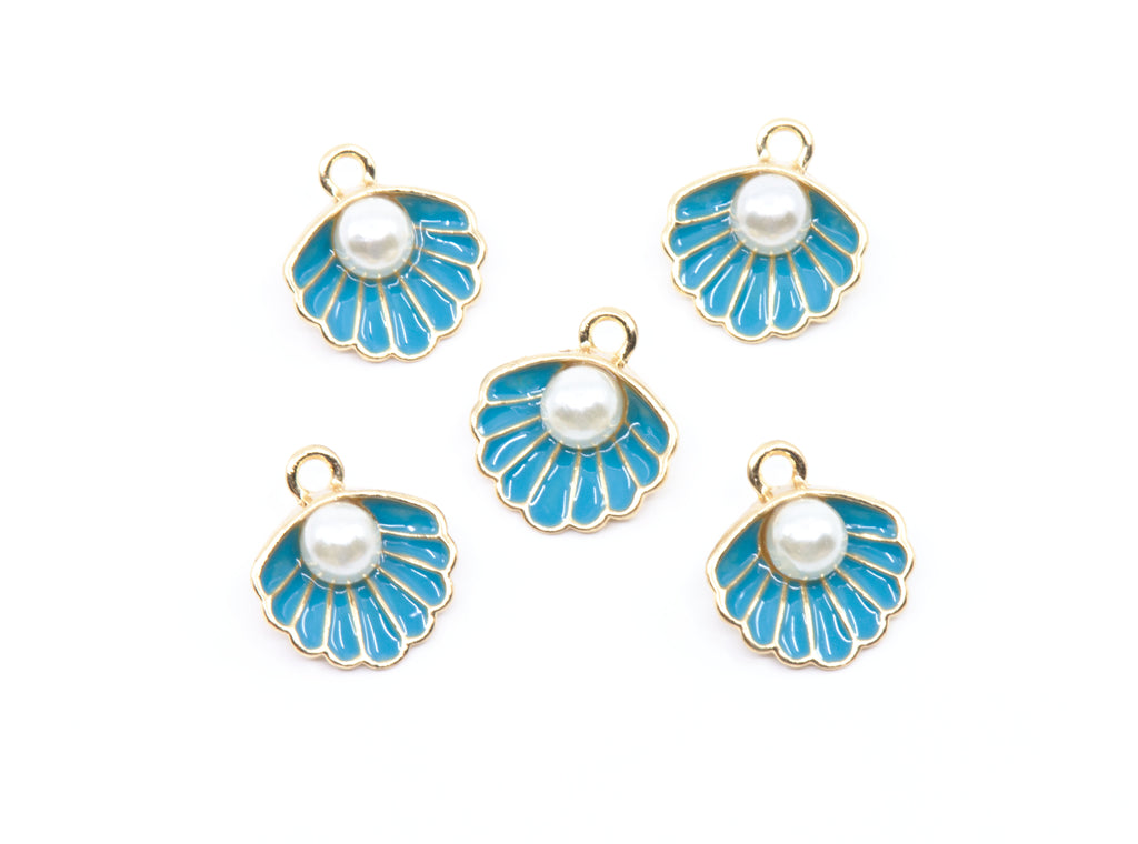 Five shell-shaped jewelry charms with bright blue enamel, white faux pearls, and gold-tone metal borders, arranged on a plain white background.