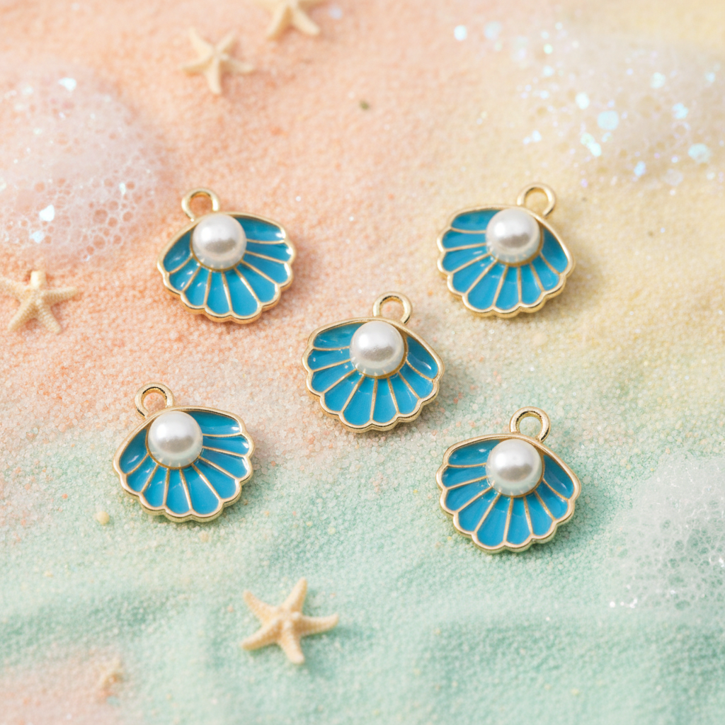 Five seashell-shaped jewelry charms with bright blue enamel, gold-tone edges, and white faux pearls, arranged on a pastel beach-themed background with starfish props.
