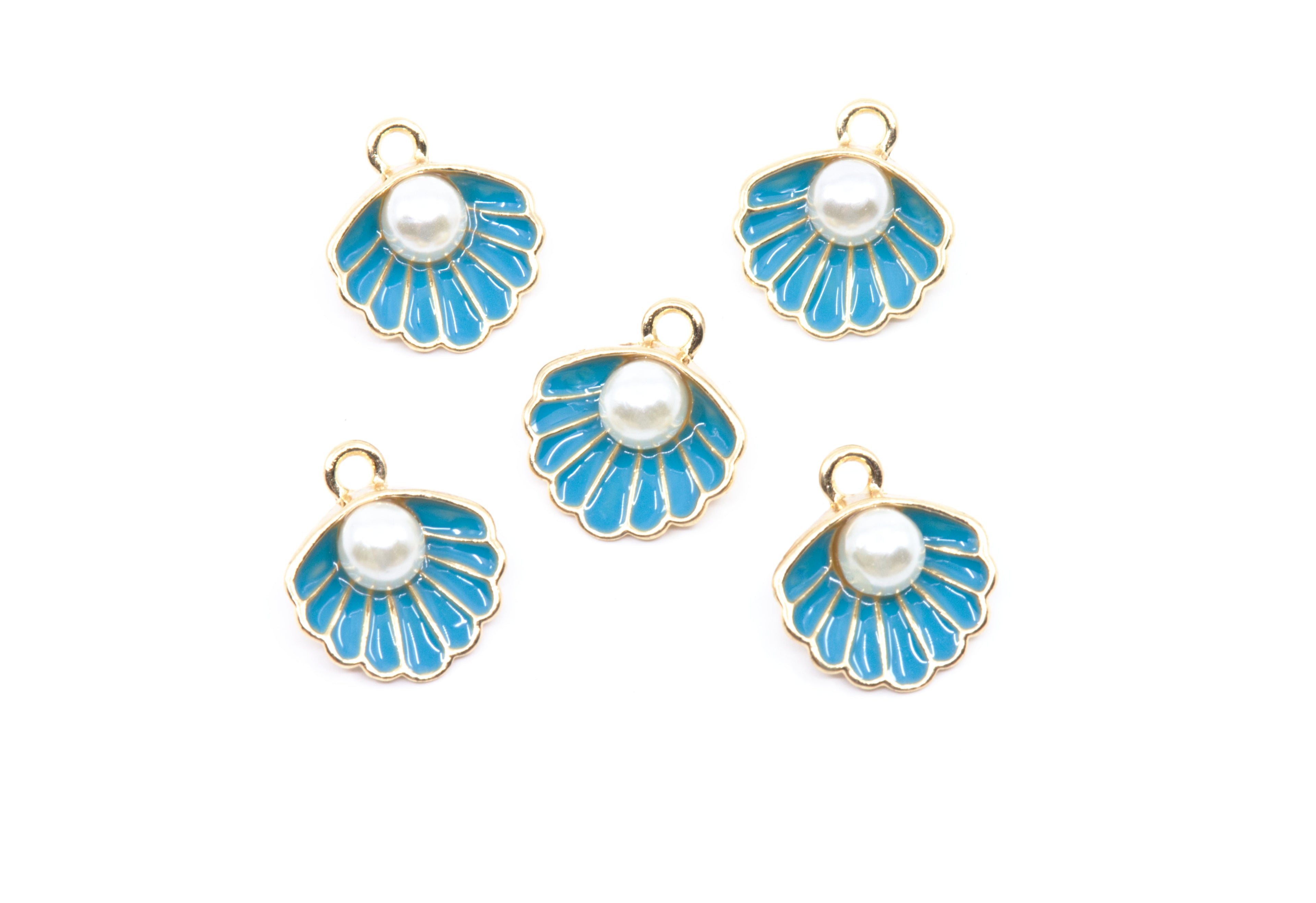 Five shell-shaped jewelry charms with bright blue enamel, white faux pearls, and gold-tone metal borders, arranged on a plain white background.