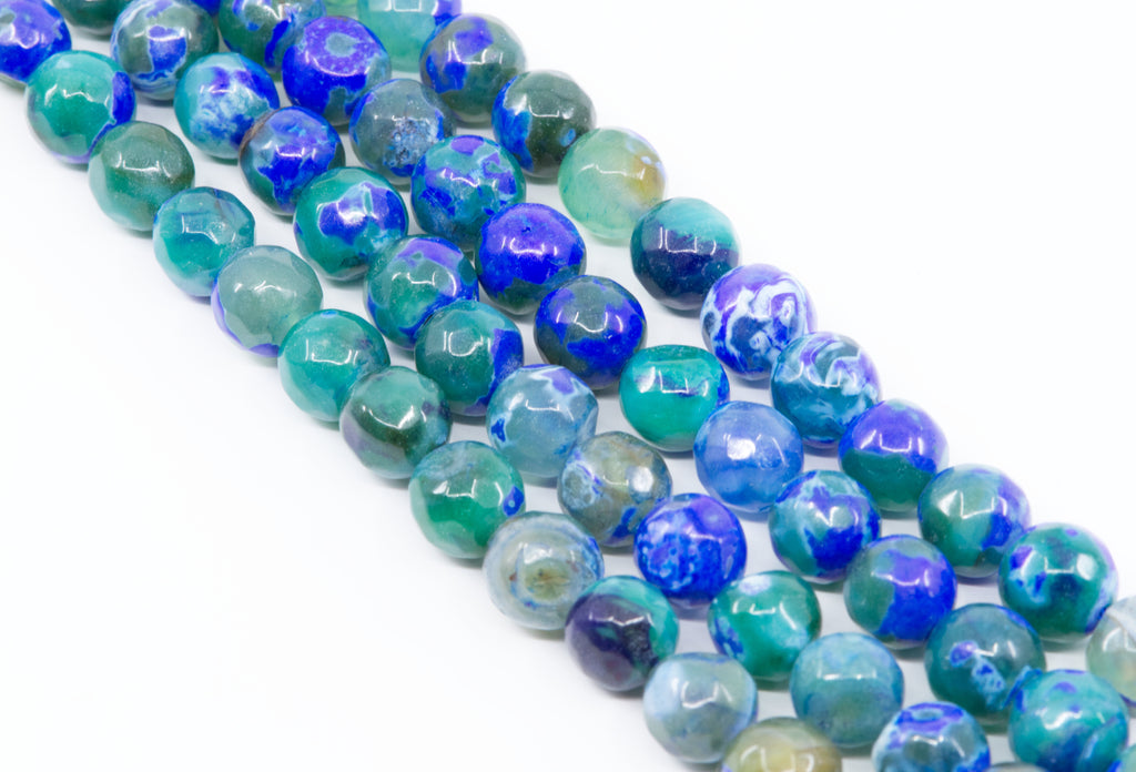Faceted round agate beads in blue, teal, and green, arranged in diagonal strands on a white background.