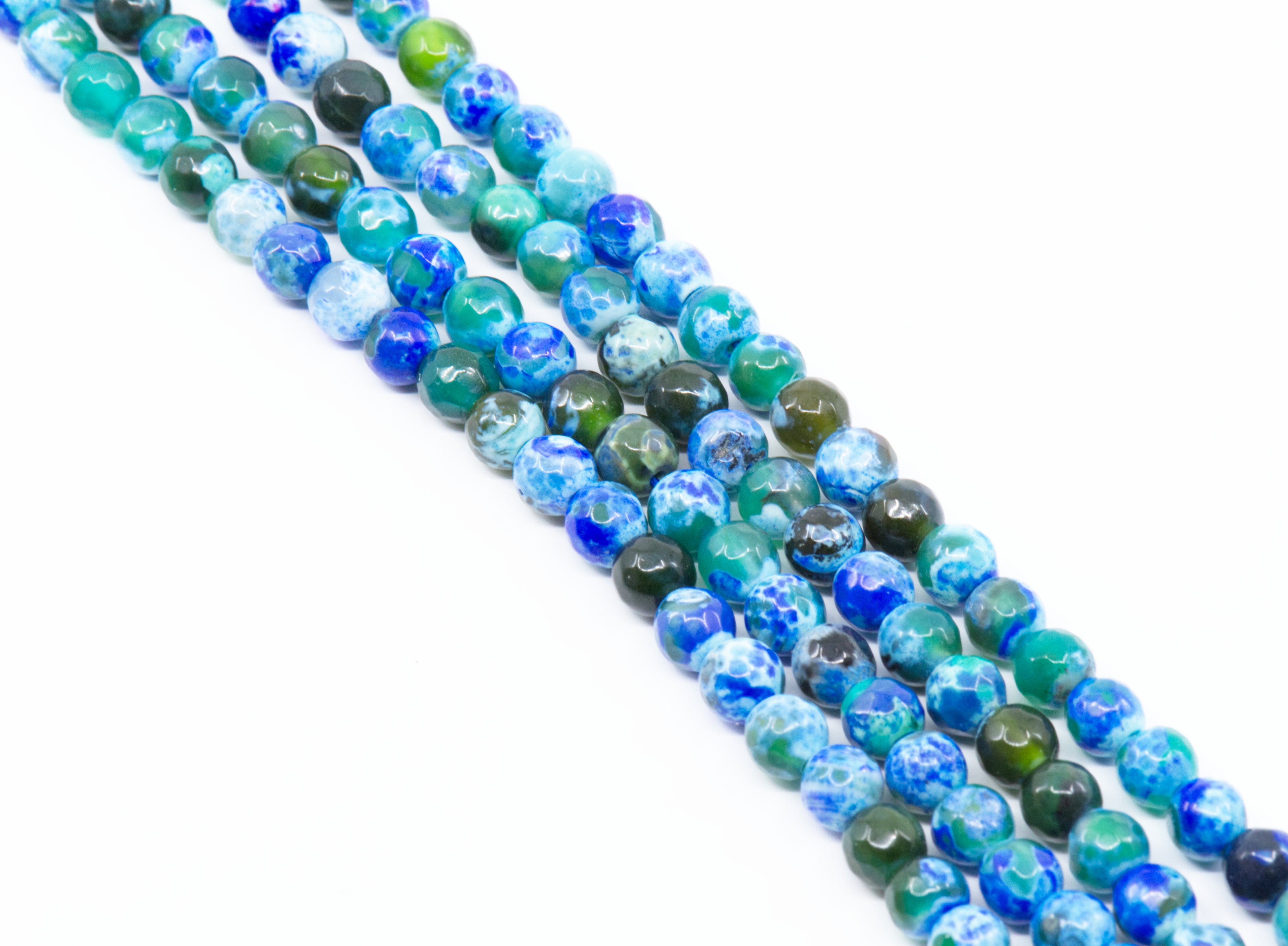 Four strands of round faceted agate beads in shades of blue and green with marbled and swirled patterns, arranged diagonally on a white background.