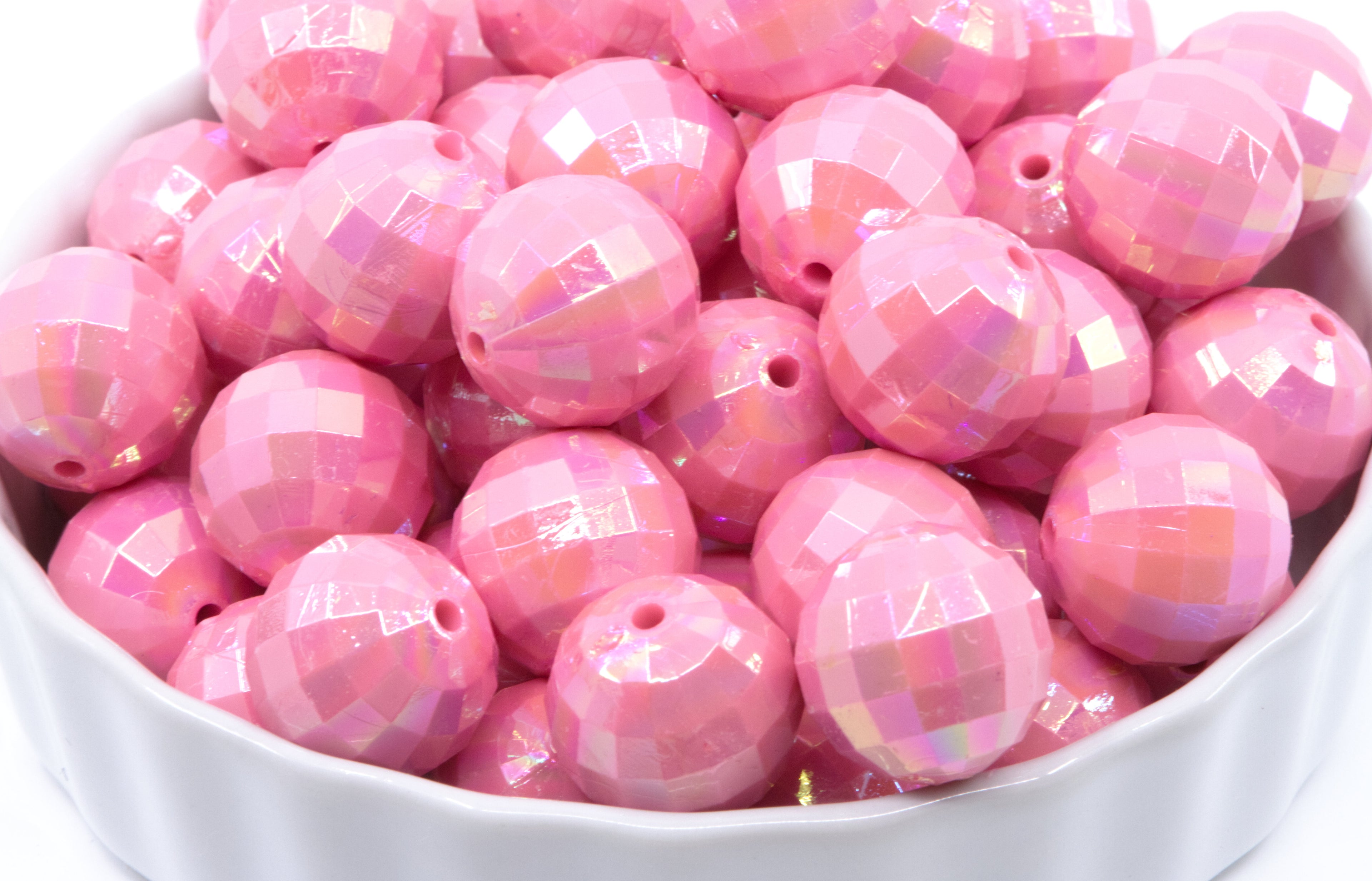 pink faceted beads in a white bowl on a white background 
