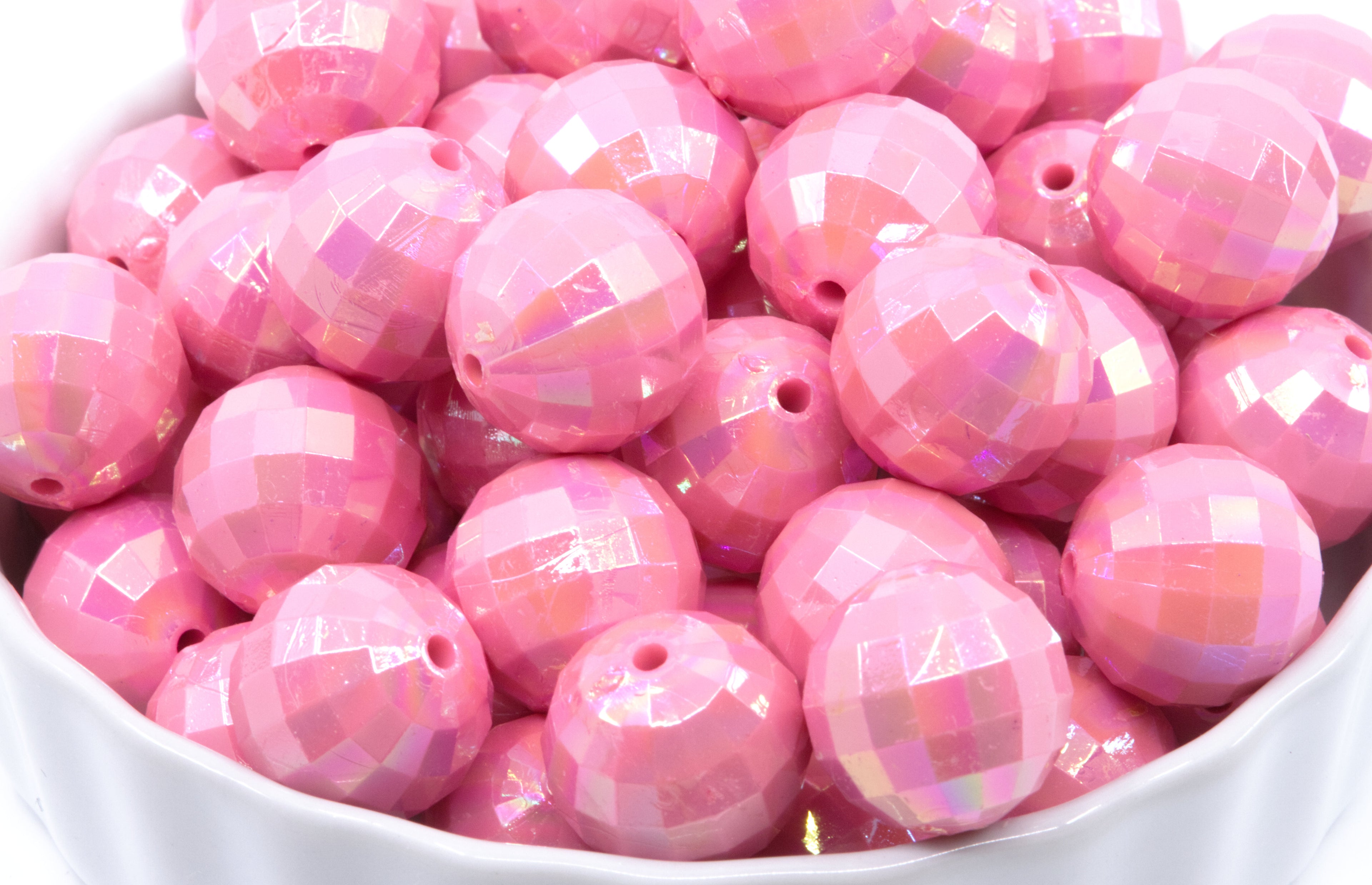Pink faceted beads in a white bowl