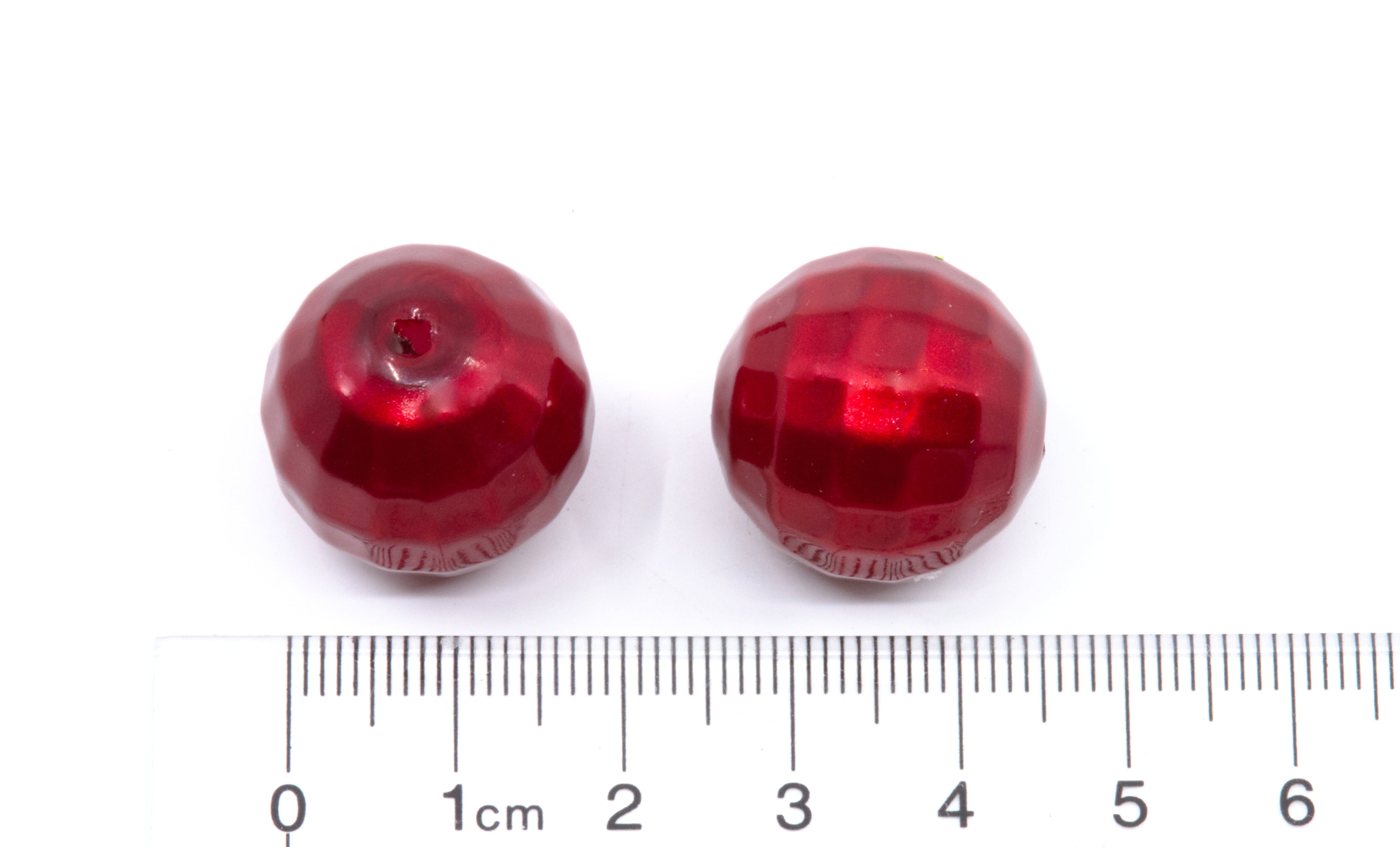 Two faceted red bubblegum beads shown next to a cm ruler for scale on a white background.