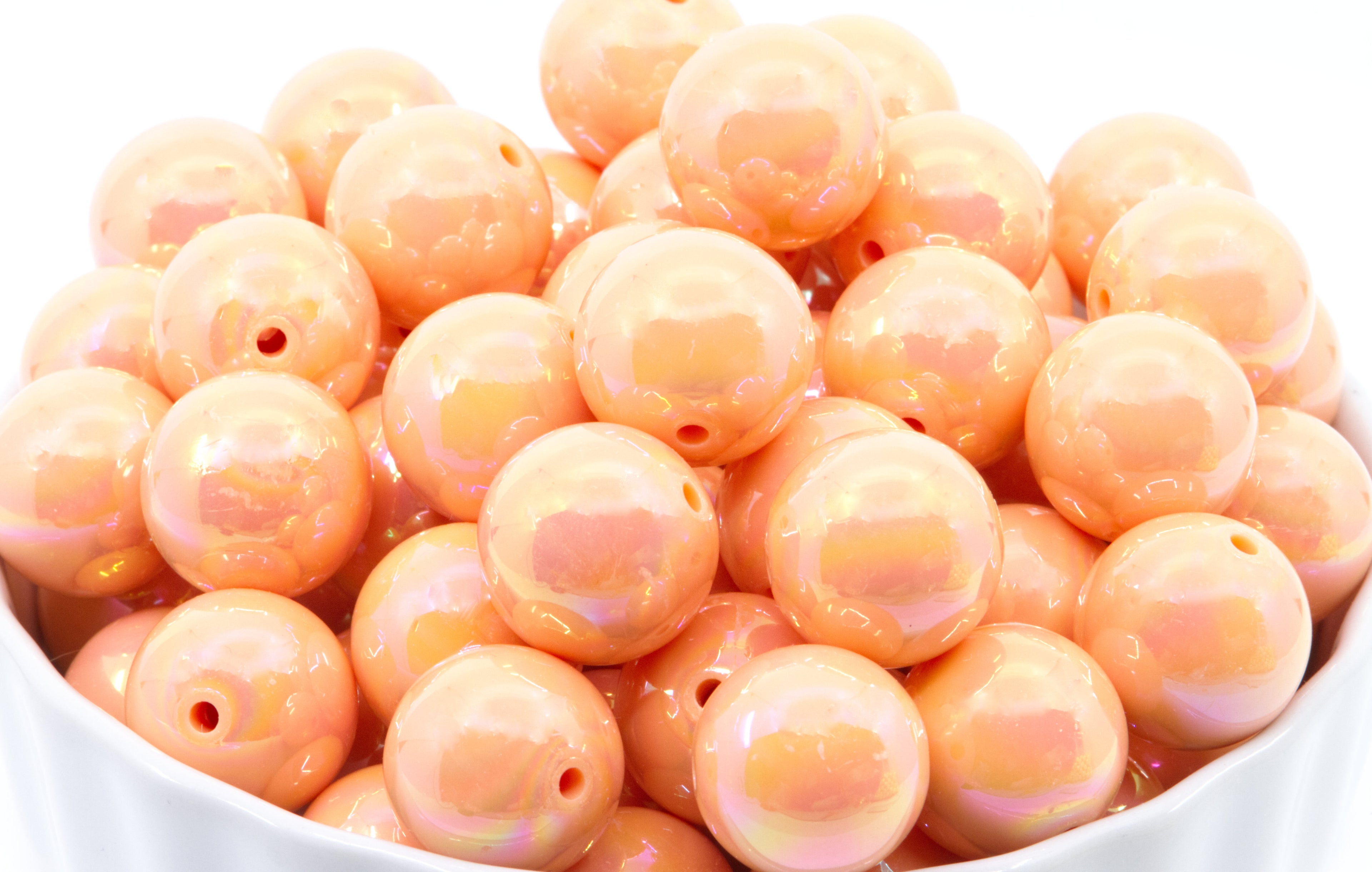 orang iridescent beads in a white bowl on a white background