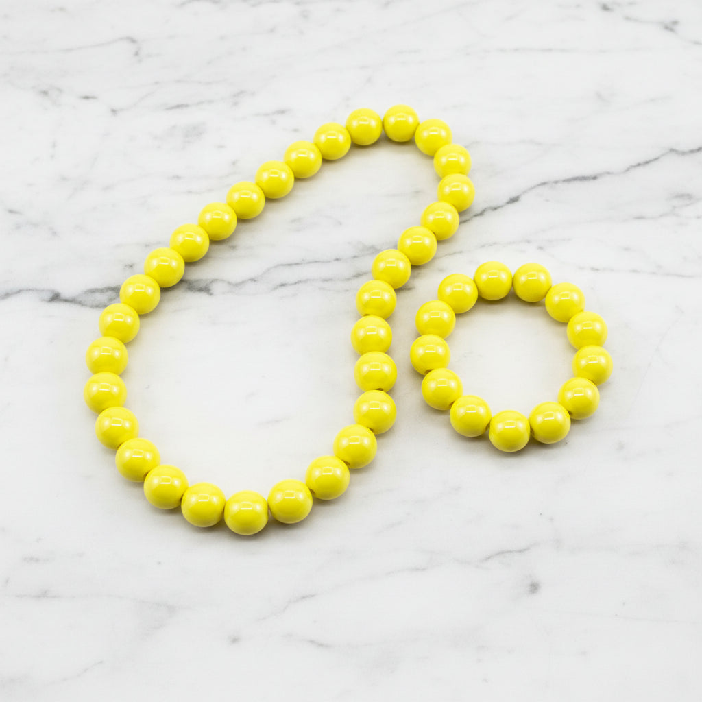 Yellow iridescent beads displayed as a necklace and bracelet on a marble background