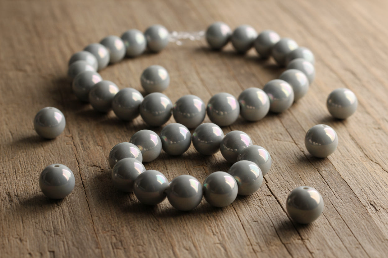 gray iridescent round beads displayed as a necklace on a woodgrain background