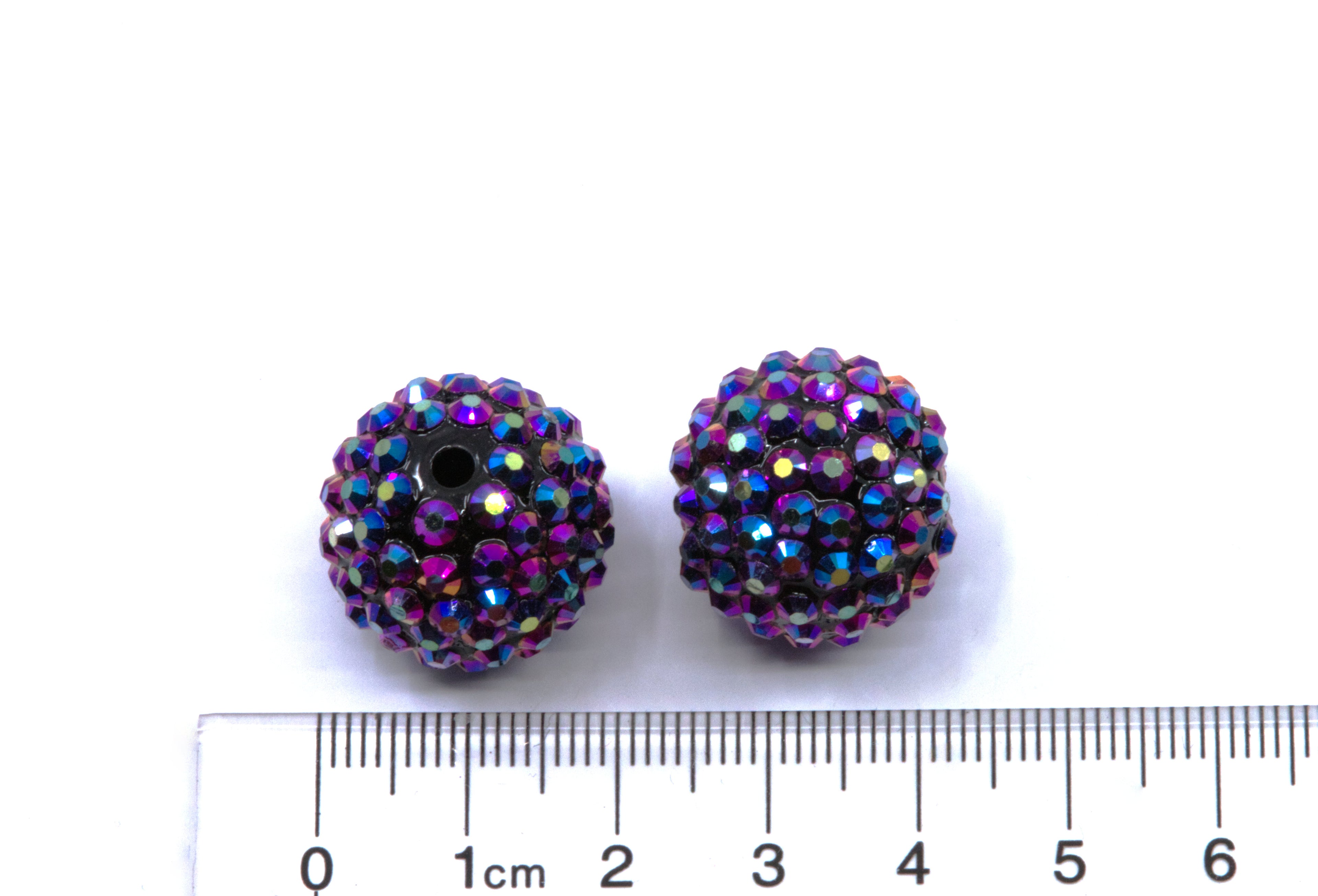 Two round metallic indigo AB rhinestone bubblegum beads, shown next to a cm ruler for scale on a white background.