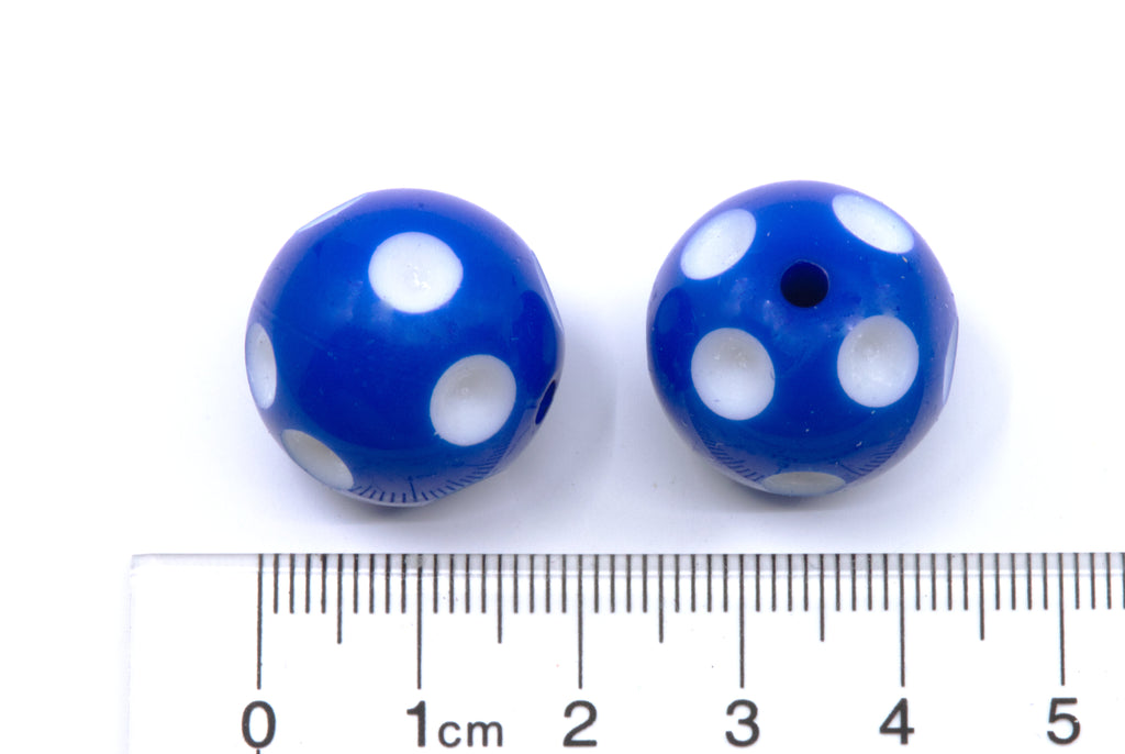 Two blue beads with white polka dots shown next to a cm ruler for scale on a white background.