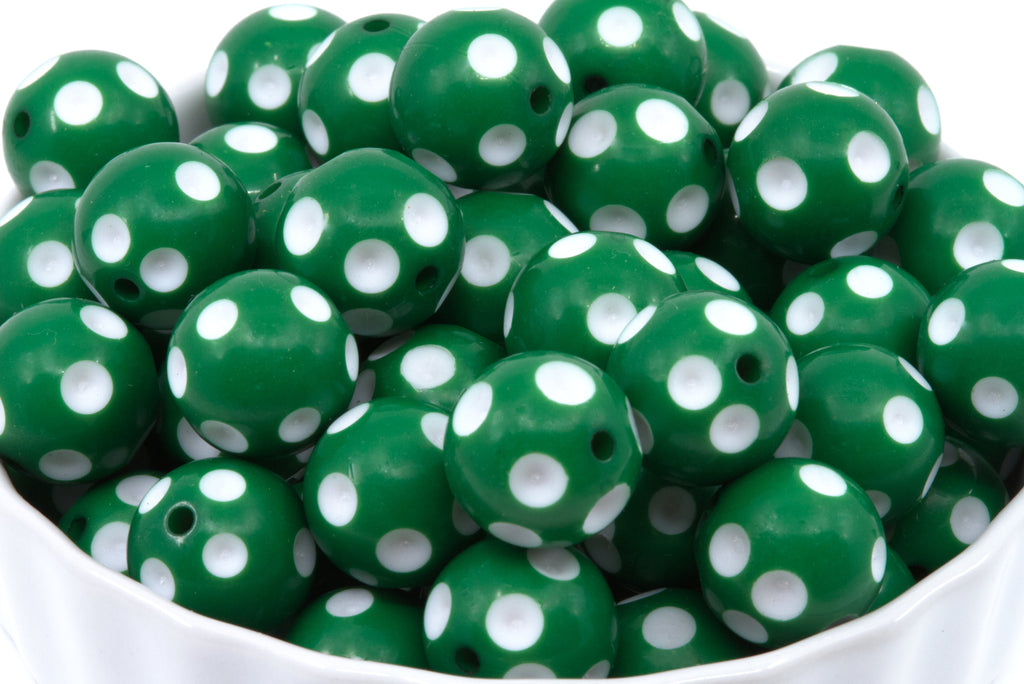 Green round beads with white polka dots, piled inside a white bowl against a white background.