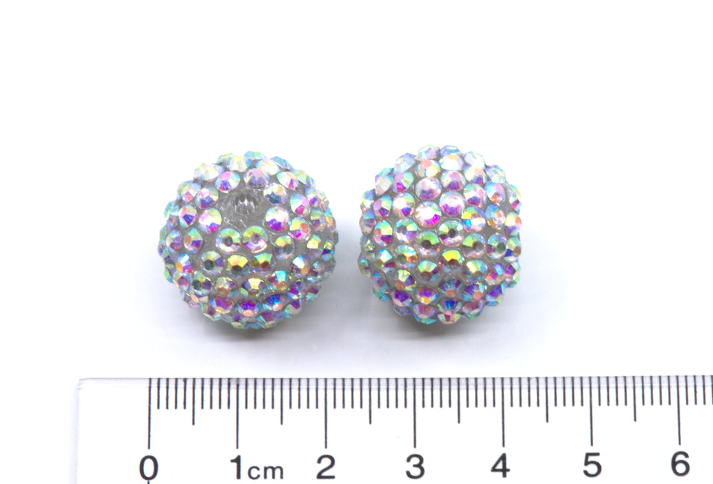Two round crystal AB rhinestone beads, shown next to a cm ruler for scale on a white background.