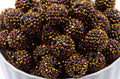 A close-up of gold AB rhinestone bubblegum beads, sitting in a white bowl.