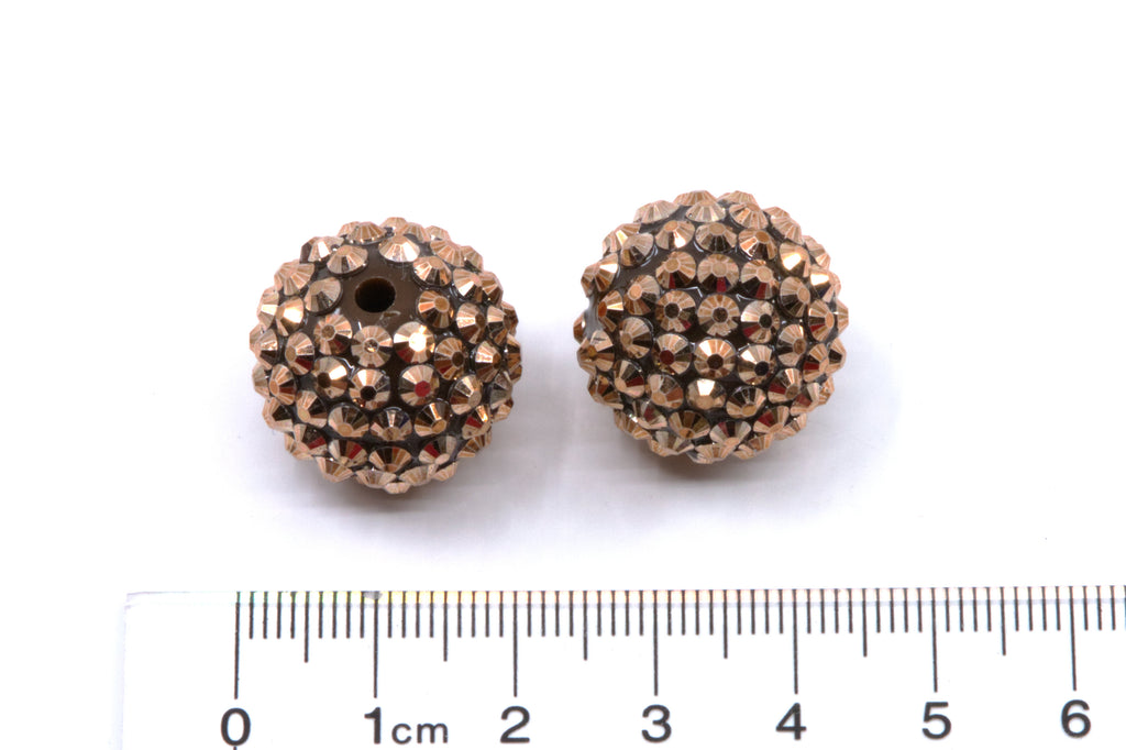 Two rose gold rhinestone beads shown next to a cm ruler for scale on a white background.