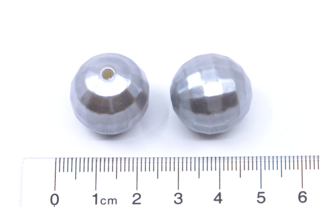 Two faceted silver-gray beads shown next to a cm ruler for scale on a white background.