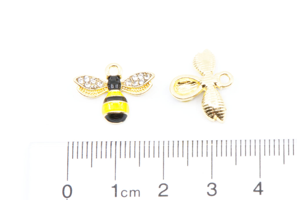 Two small bee-shaped jewelry charms shown on a white background with a 1cm ruler below for scale. 
