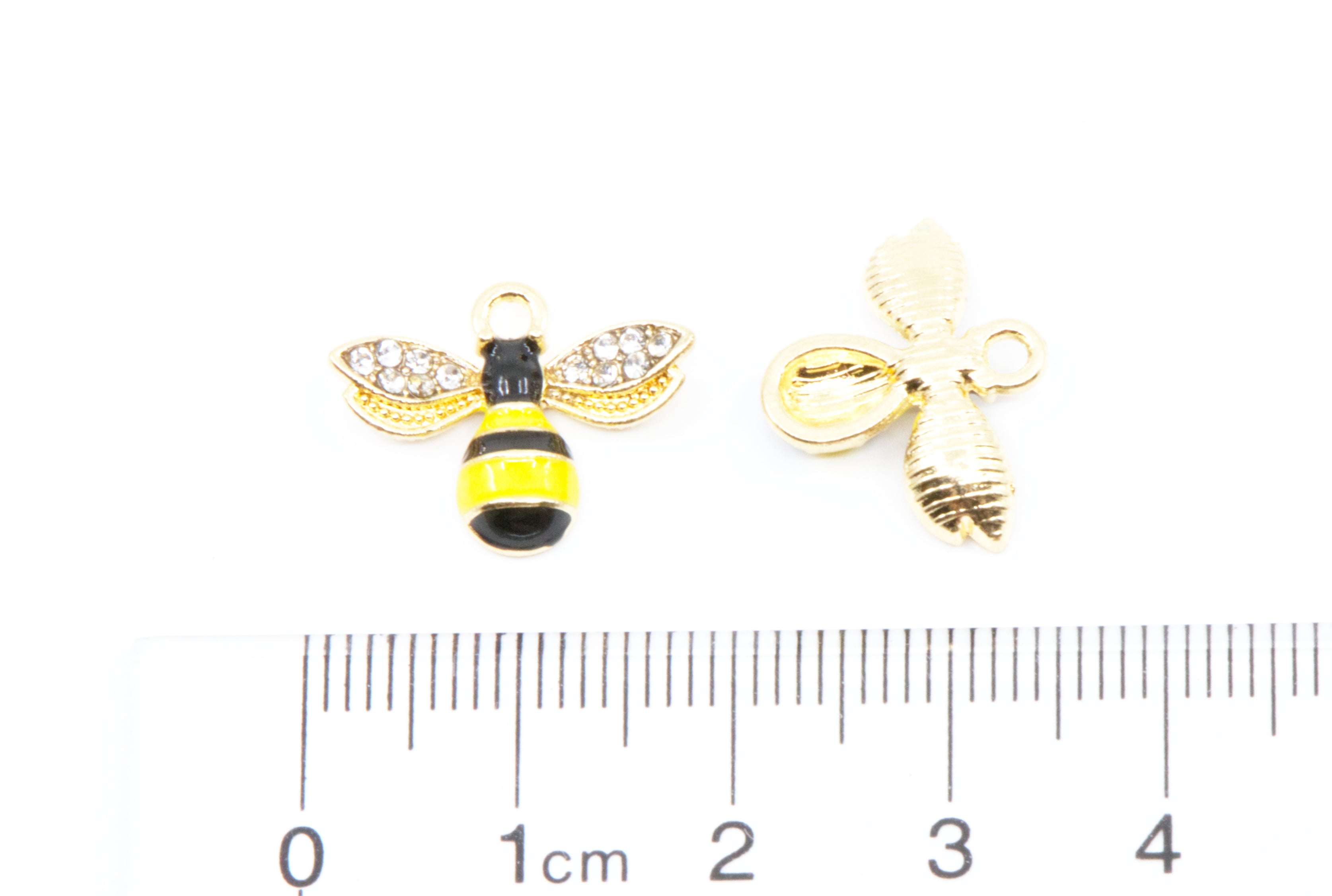 Two small bee-shaped jewelry charms shown on a white background with a 1cm ruler below for scale. 