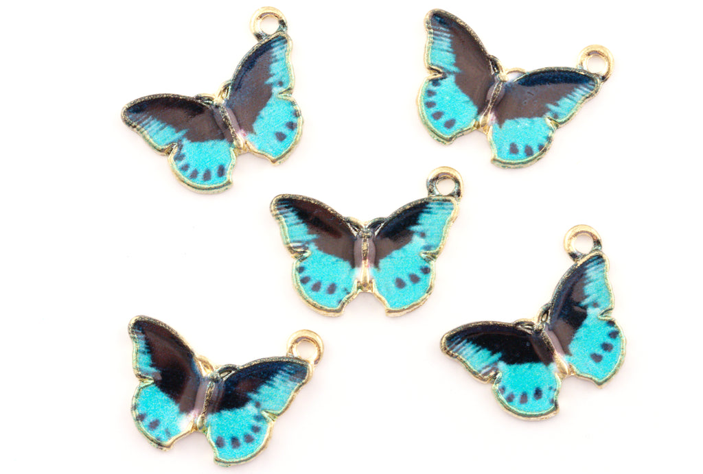 Five butterfly-shaped jewelry charms with blue and black enamel wings, outlined in gold-tone metal, arranged on a plain white background.
