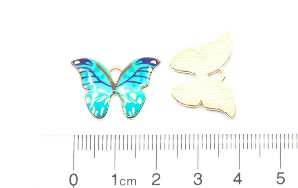 Two butterfly-shaped jewelry charms shown on a white background with a ruler at the bottom for scale. 