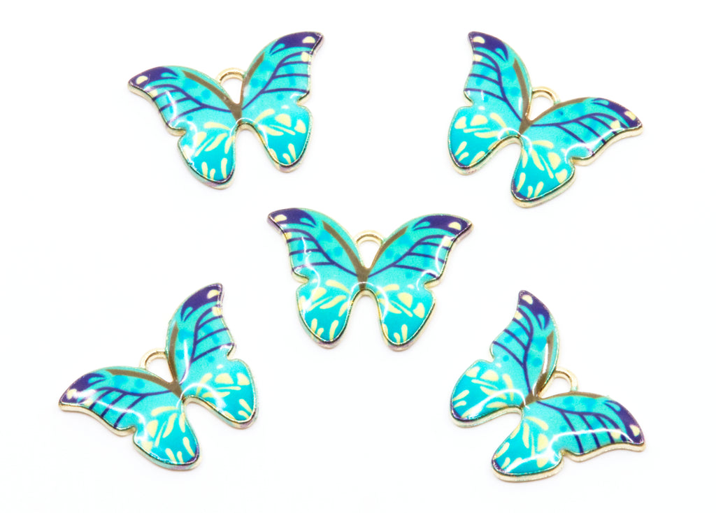 Five butterfly-shaped jewelry charms with blue and green enamel wings and gold-tone edges, arranged on a plain white background.