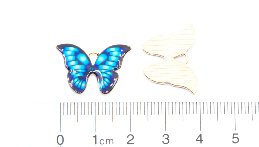 Two blue butterfly charms shown on a white background with a ruler at the bottom for scale