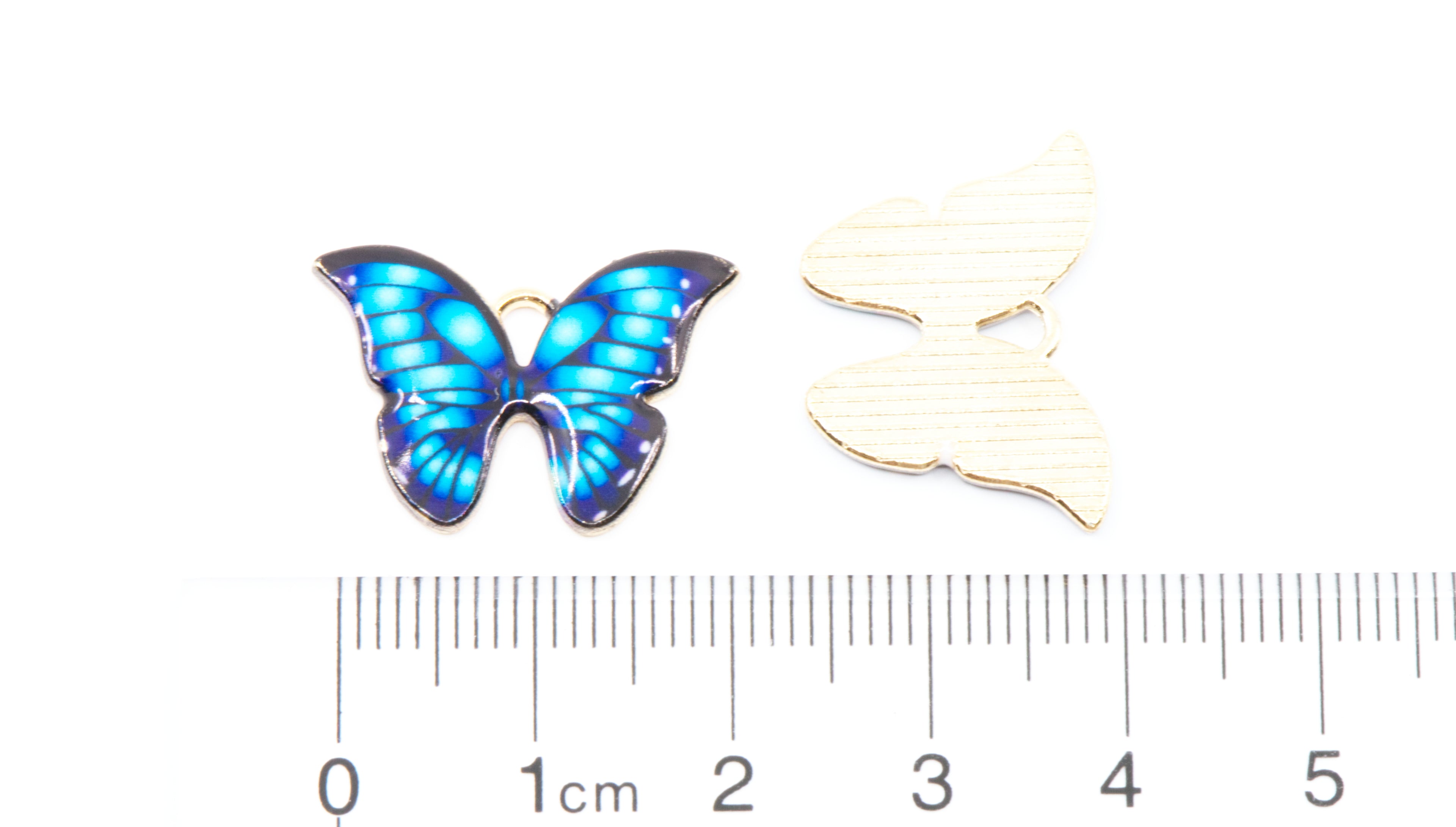 Two blue butterfly charms shown on a white background with a ruler at the bottom for scale