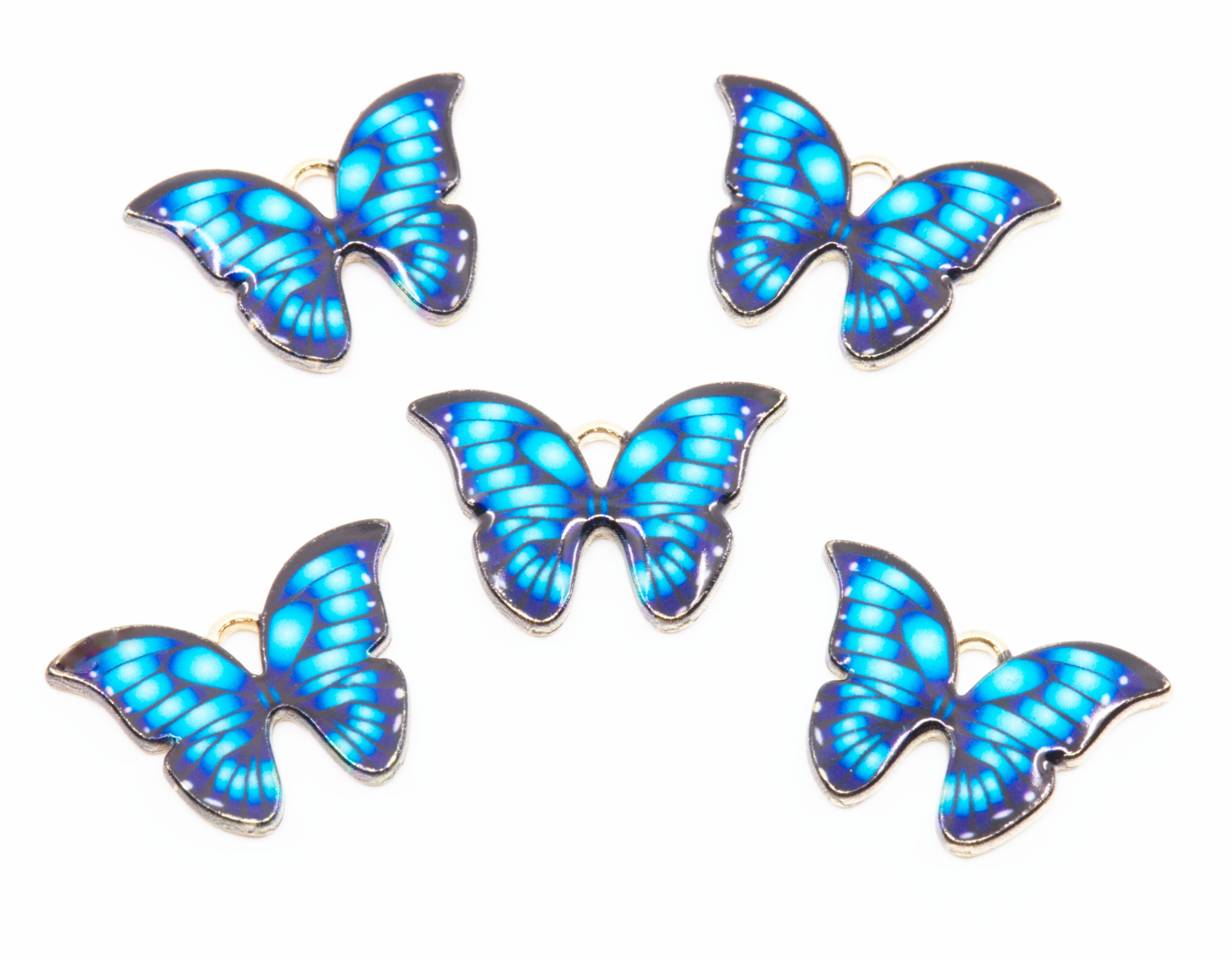 Five butterfly-shaped jewelry charms with vibrant blue and light blue patterned wings and gold-tone metal edges, arranged on a plain white background.