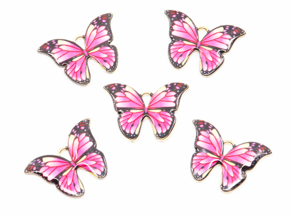 Five butterfly charms with pink e wings, black borders, and gold metal outlines, arranged on a plain white background.