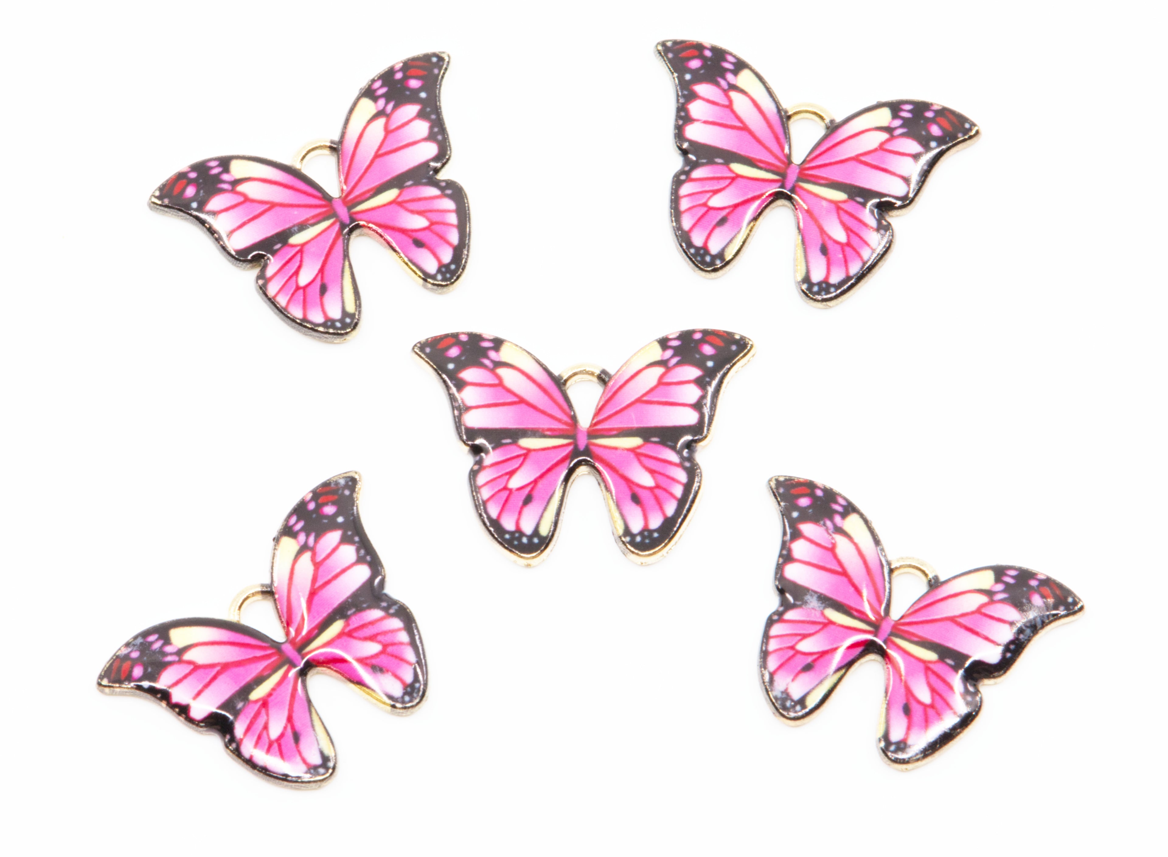 Five butterfly charms with pink e wings, black borders, and gold metal outlines, arranged on a plain white background.