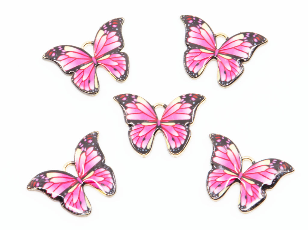 Five butterfly charms with pink e wings, black borders, and gold metal outlines, arranged on a plain white background.
