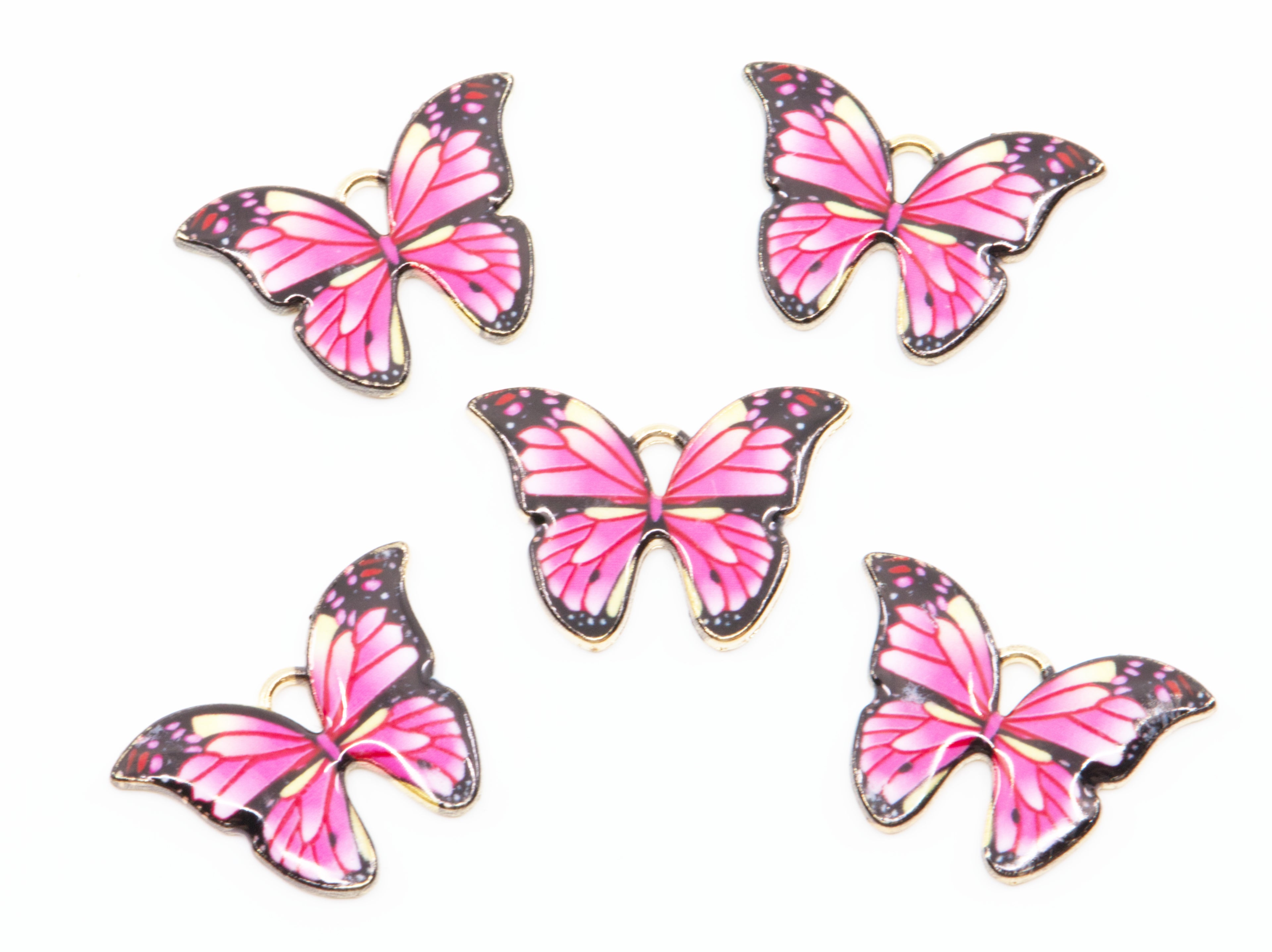 Five butterfly charms with pink e wings, black borders, and gold metal outlines, arranged on a plain white background.