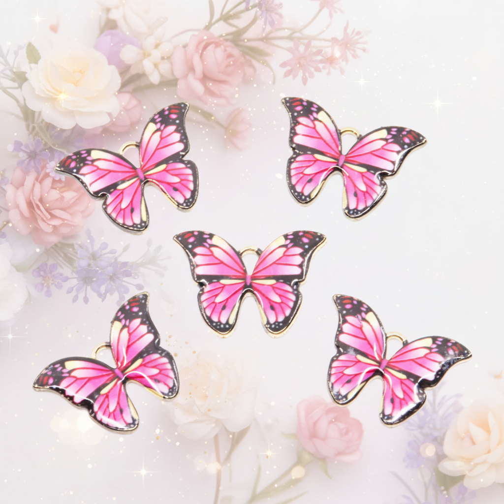 Five pink and black butterfly-shaped charms with gold-tone edges, arranged on a white background with soft pastel flowers and sparkles.