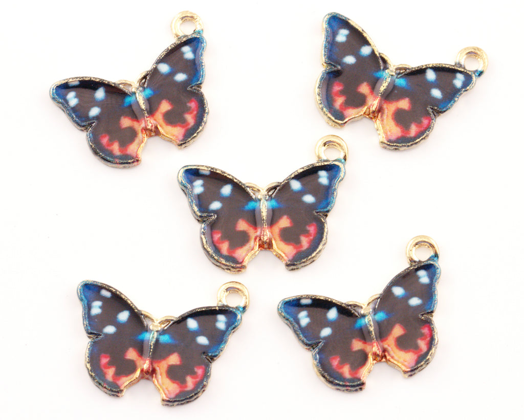 Five butterfly-shaped jewelry charms with gold-tone edges and loops, featuring a black wing pattern with blue, orange, and white details, on a plain white background.