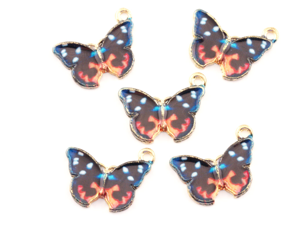Five butterfly-shaped jewelry charms with gold-tone edges and loops, featuring a black wing pattern with blue, orange, and white details, on a plain white background.