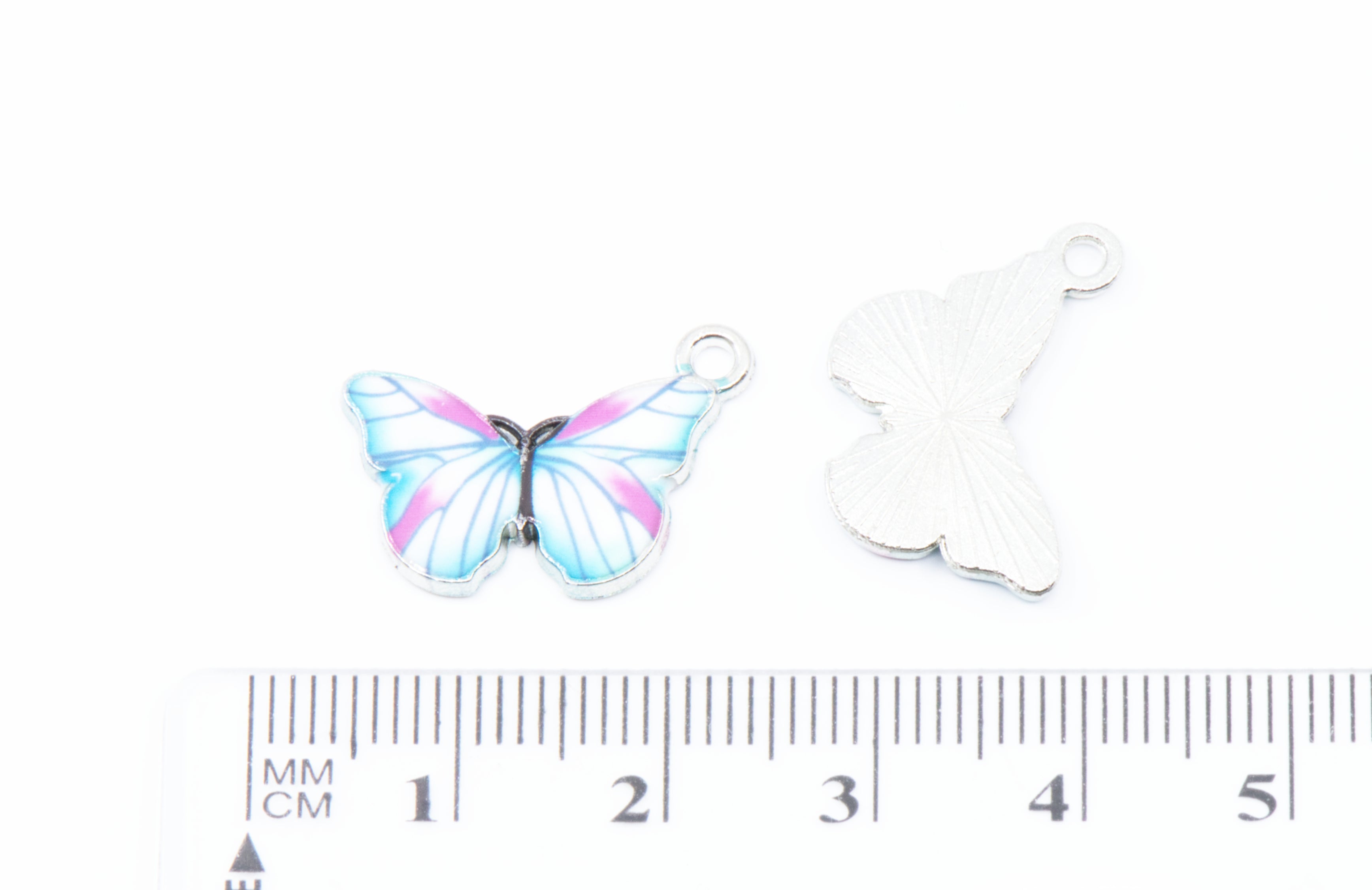 Two butterfly-shaped jewelry charms on a white background. A small ruler is shown below for scale.