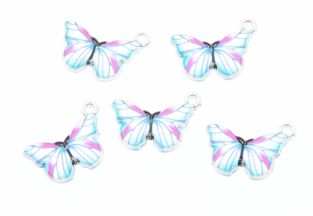 Five butterfly-shaped jewelry charms with silver-toned metal loops, featuring light blue, purple, and white wing patterns on a white background.