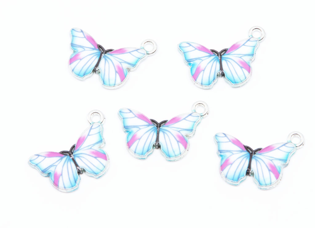 Five butterfly-shaped jewelry charms with silver-toned metal loops, featuring light blue, purple, and white wing patterns on a white background.