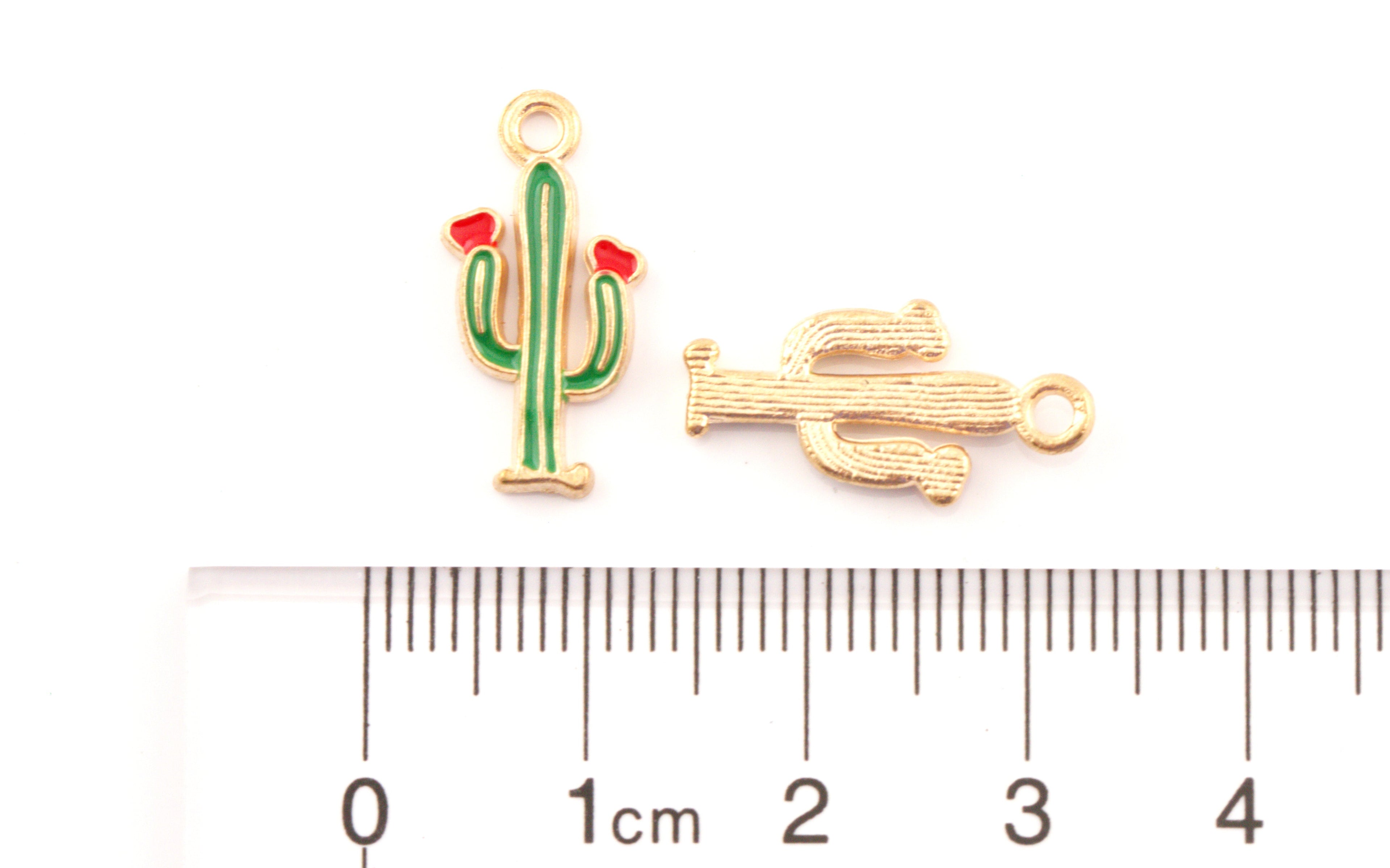 Two small cactus-shaped jewelry findings or charms shown above a ruler for scale on a white background. 