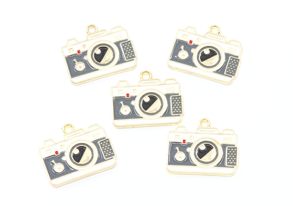 Five camera-shaped jewelry charms with gold-tone metal borders and dark gray enamel details, arranged on a plain white background.