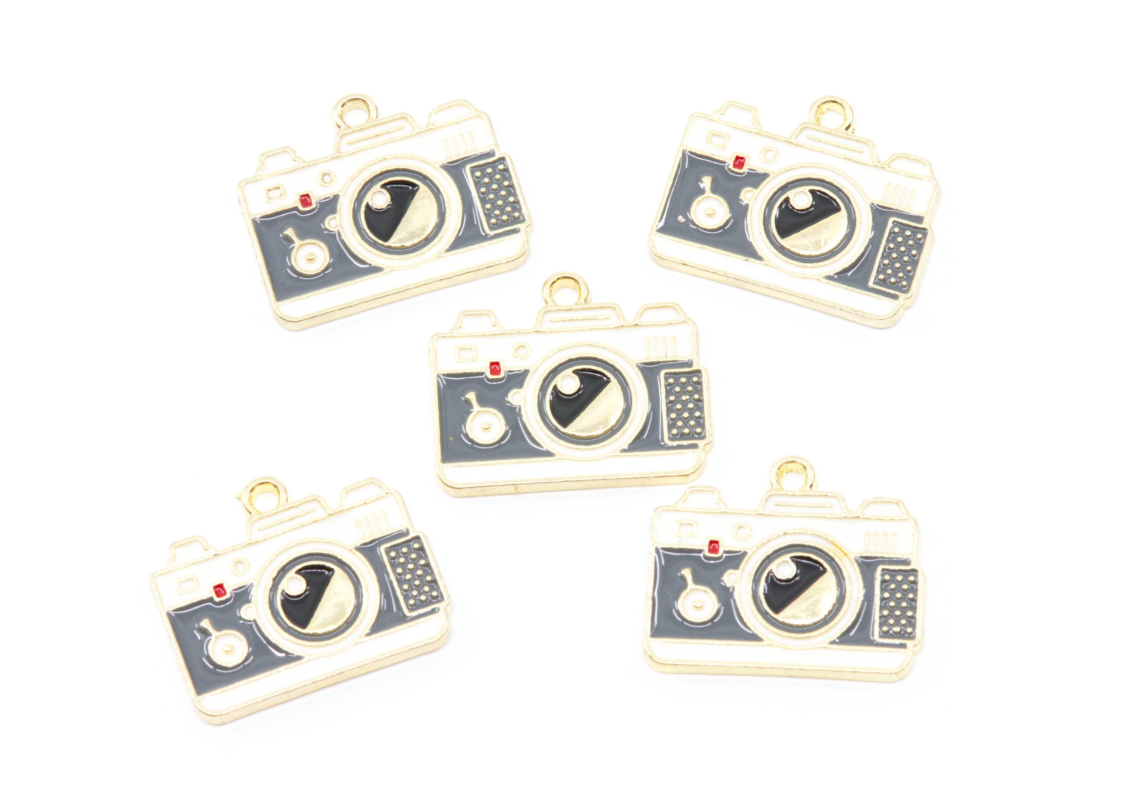 Five camera-shaped jewelry charms with gold-tone metal borders and dark gray enamel details, arranged on a plain white background.