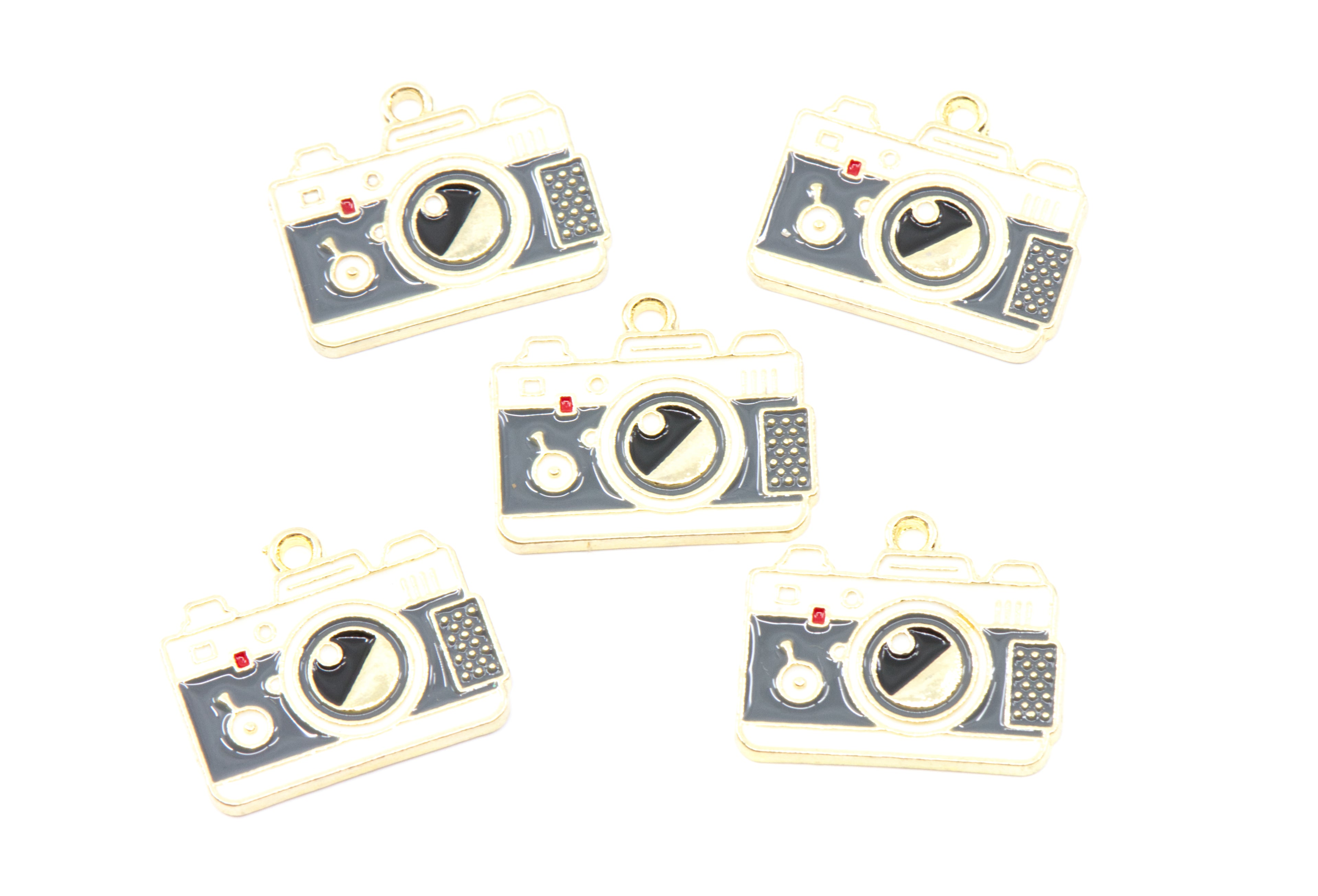 Five camera-shaped jewelry charms with gold-tone metal borders and dark gray enamel details, arranged on a plain white background.