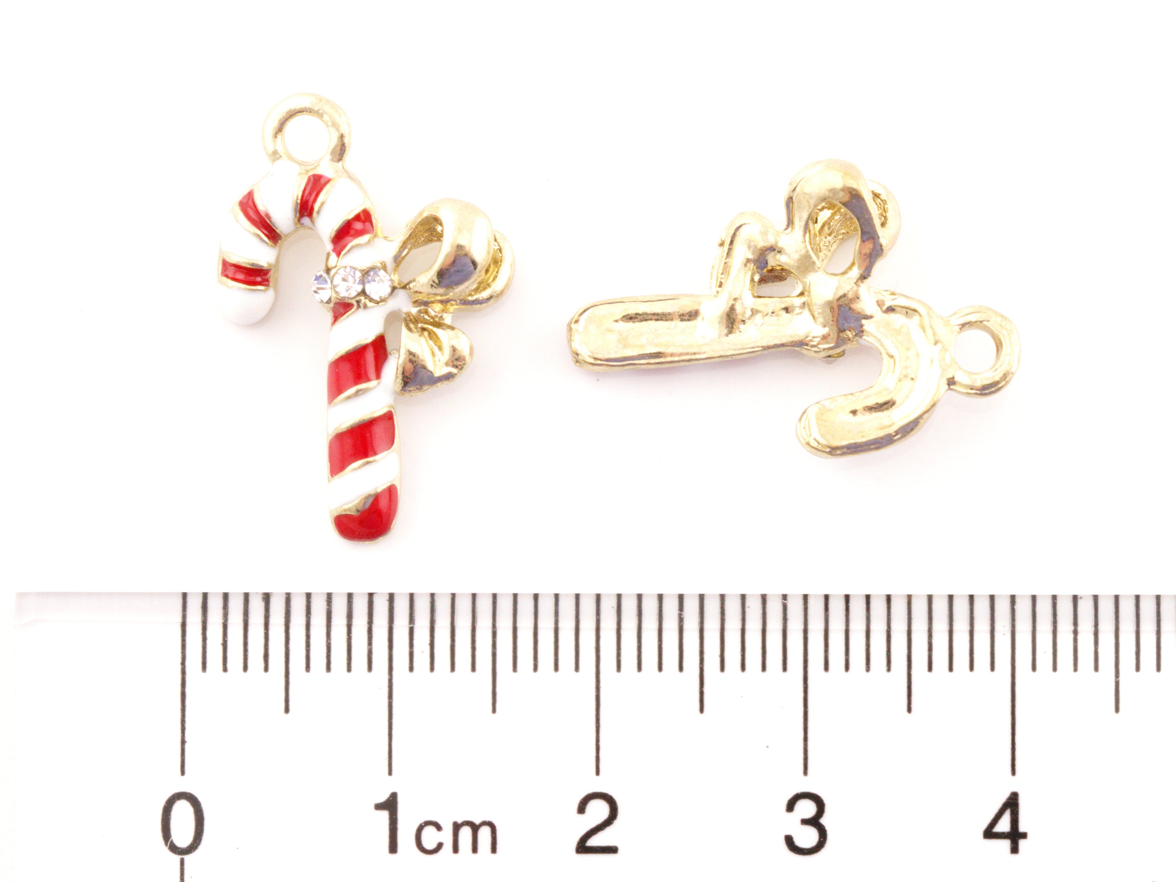 Two small gold-tone candy cane charms with red and white enamel stripes and a clear rhinestone accent, shown beside a cm ruler for scale on a white background.