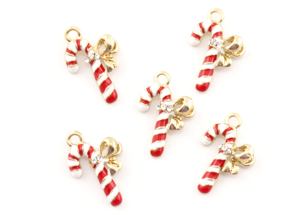 Five candy cane jewelry charms with red and white stripes, gold-tone bows, and small clear rhinestones, arranged on a plain white background.