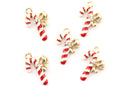 Five candy cane jewelry charms with red and white stripes, gold-tone bows, and small clear rhinestones, arranged on a plain white background.