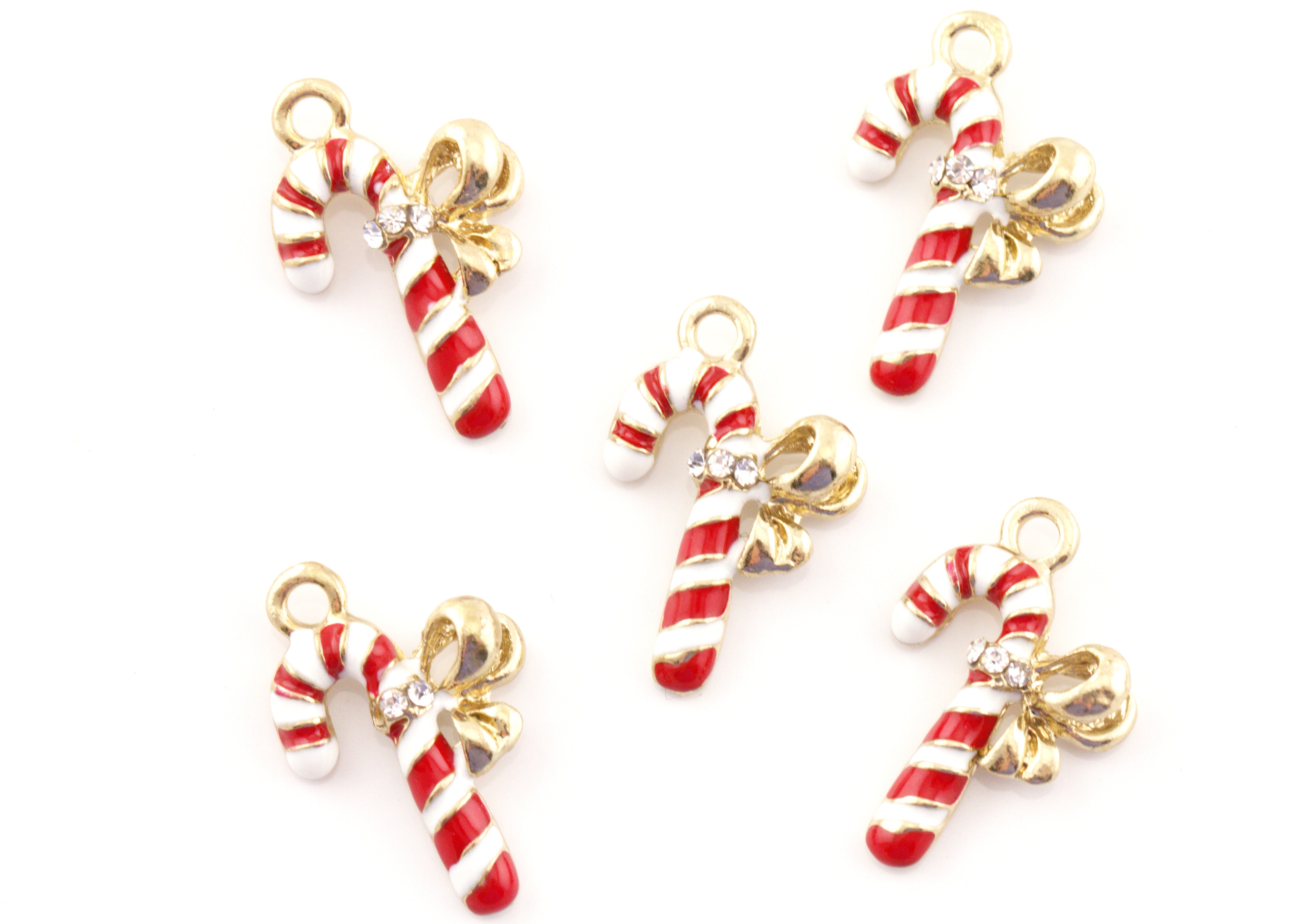 Five candy cane jewelry charms with red and white stripes, gold-tone bows, and small clear rhinestones, arranged on a plain white background.