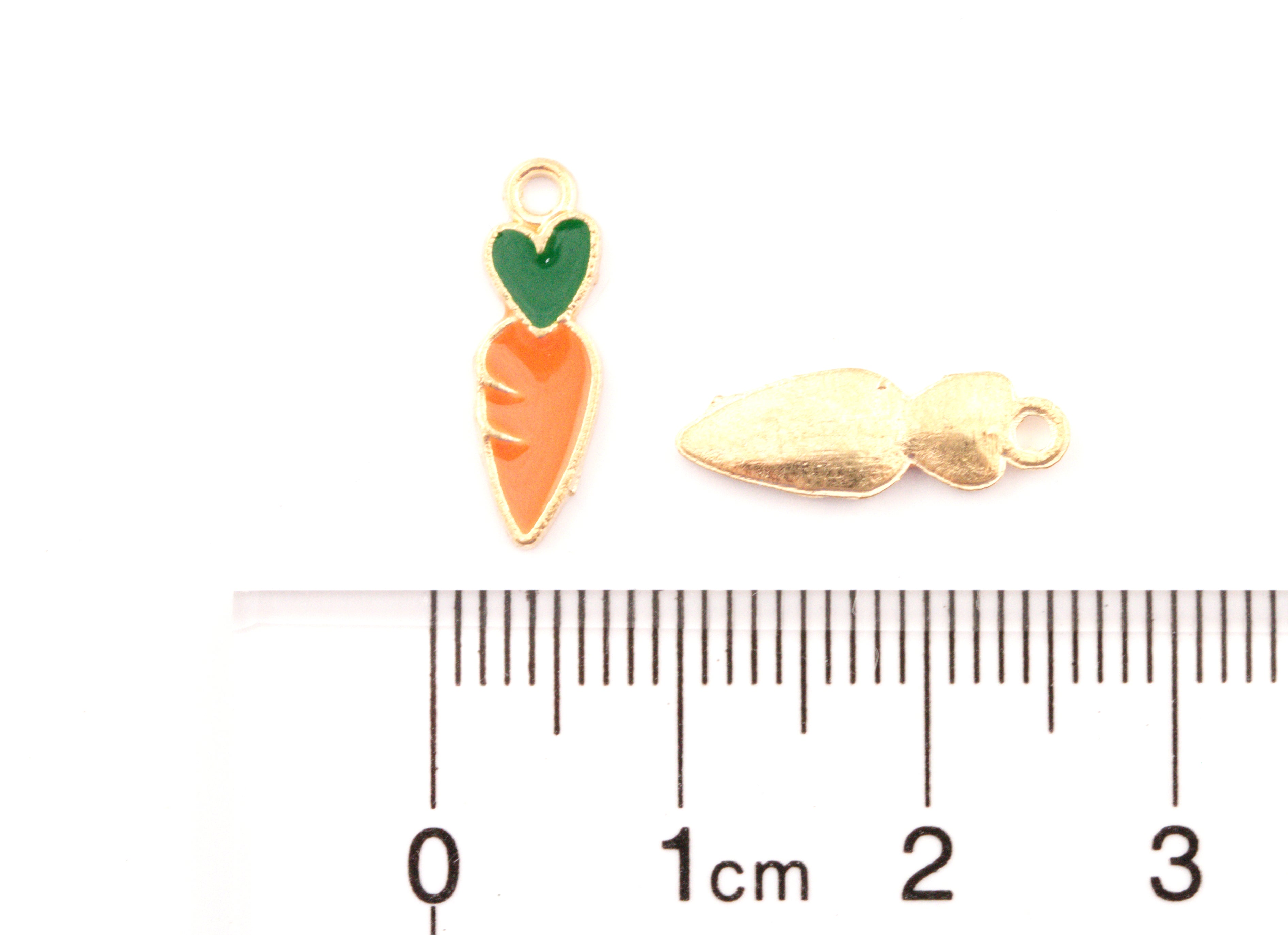 Two small carrot-shaped jewelry charms with gold-tone metal borders and enamel details are shown above a cm ruler for scale.