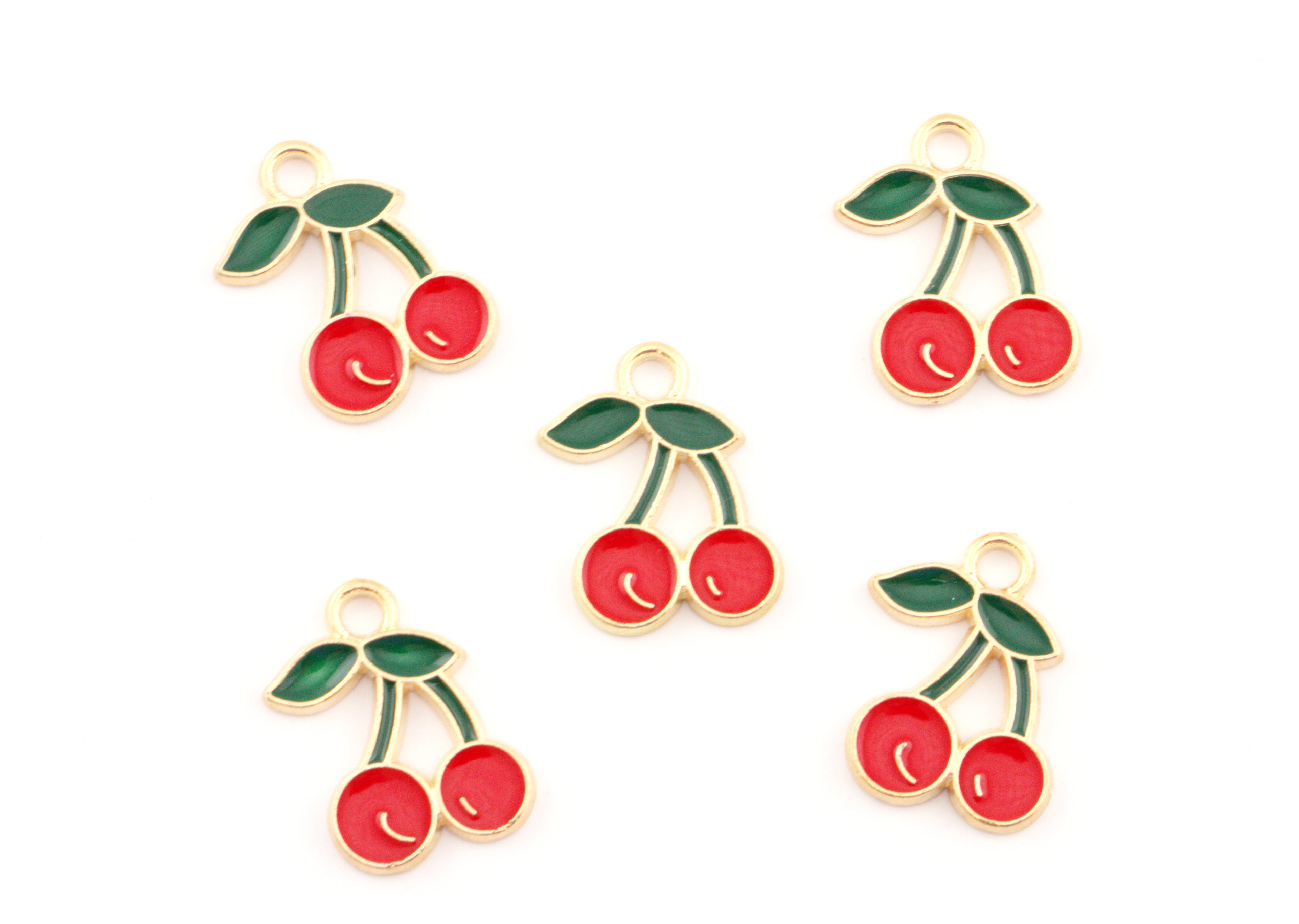 Five cherry-shaped jewelry charms with red enamel, green leaves, and gold-tone metal borders arranged on a plain white background.