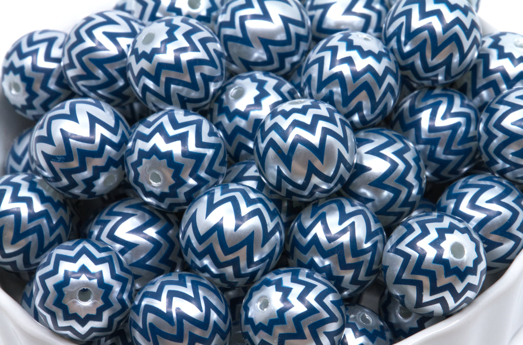 A pile of bubblegum beads with a blue and silver chevron pattern, sitting in a white container.