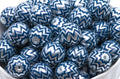 A pile of bubblegum beads with a blue and silver chevron pattern, sitting in a white container.