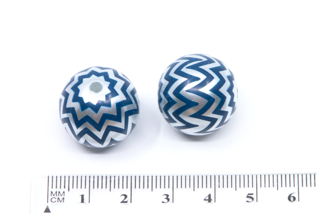 Two round bubblegum beads with a blue and silver chevron pattern, shown next to a cm ruler for scale on a white background.